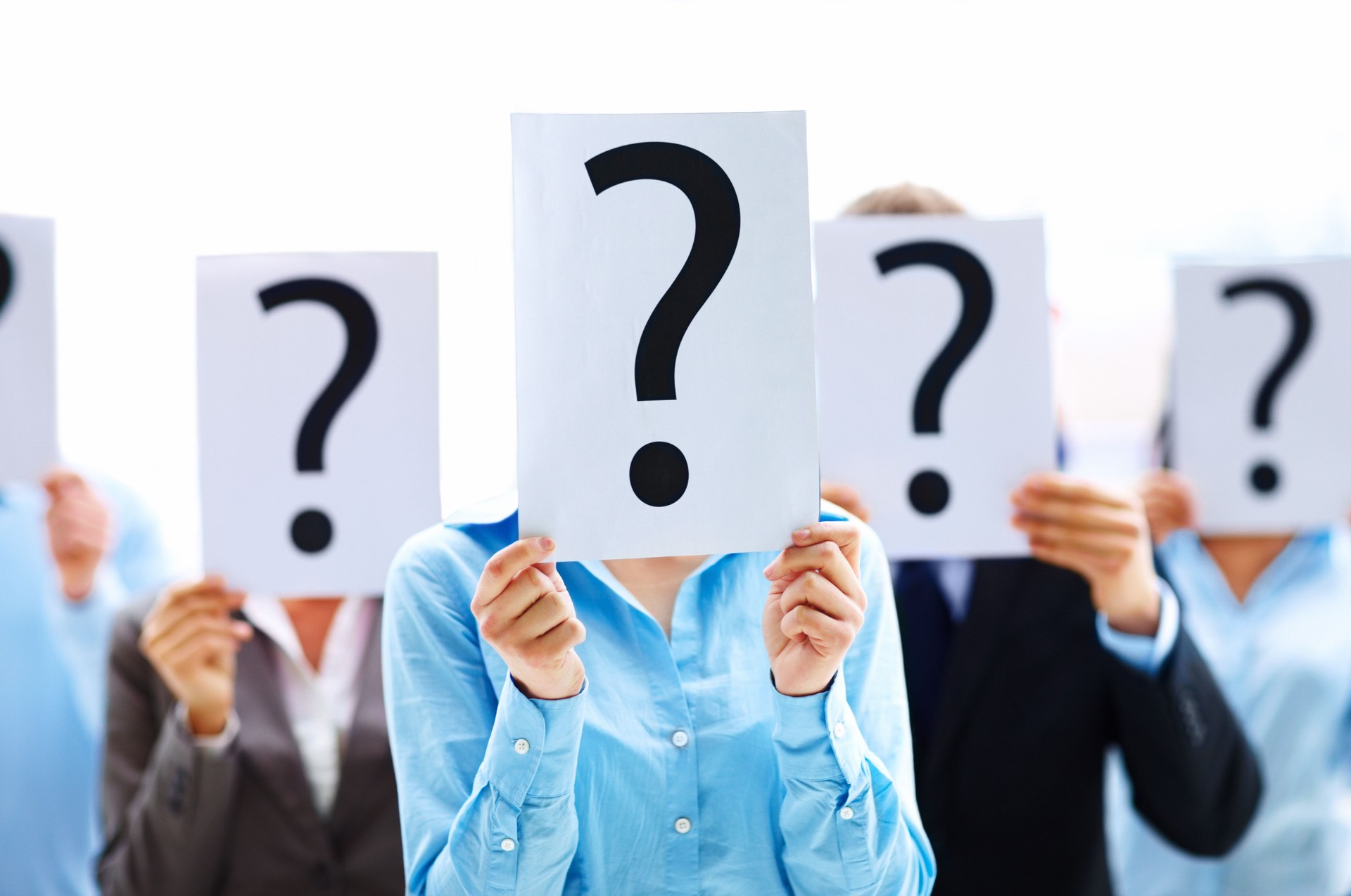 Colleagues holding question mark signs in front of their faces